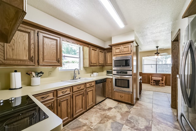 kitchen featuring ceiling fan, appliances with stainless steel finishes, a sink, and a healthy amount of sunlight