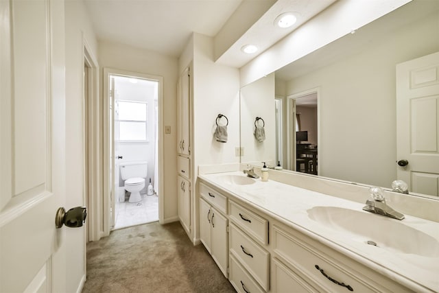 full bath with toilet, a sink, double vanity, and baseboards