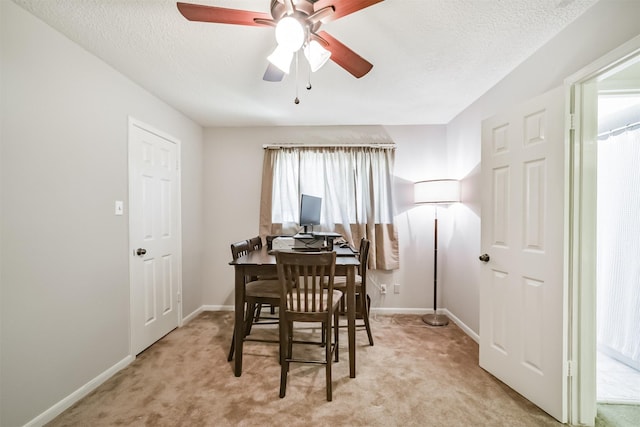 dining area with ceiling fan, light carpet, a textured ceiling, and baseboards