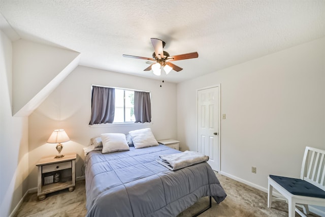 bedroom with light colored carpet, ceiling fan, baseboards, and a textured ceiling