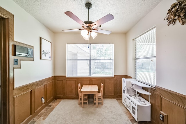 interior space with a textured ceiling, a wealth of natural light, and wainscoting
