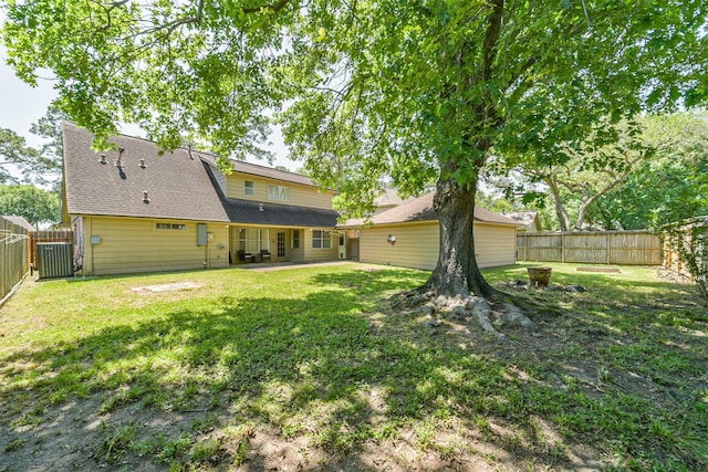 rear view of property with a fire pit, a yard, a fenced backyard, and a patio