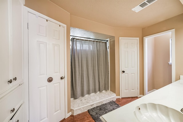bathroom featuring wood finished floors, a sink, curtained shower, baseboards, and visible vents