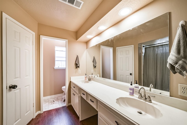 bathroom featuring visible vents, toilet, baseboards, and a sink