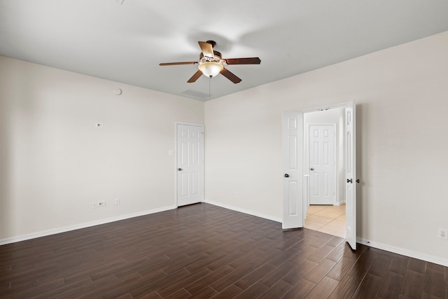 empty room with a ceiling fan, baseboards, and dark wood-style flooring