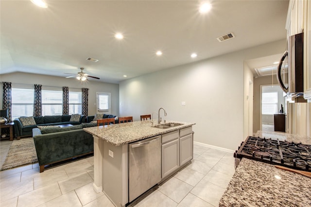kitchen featuring visible vents, a sink, ceiling fan, stainless steel appliances, and light stone counters