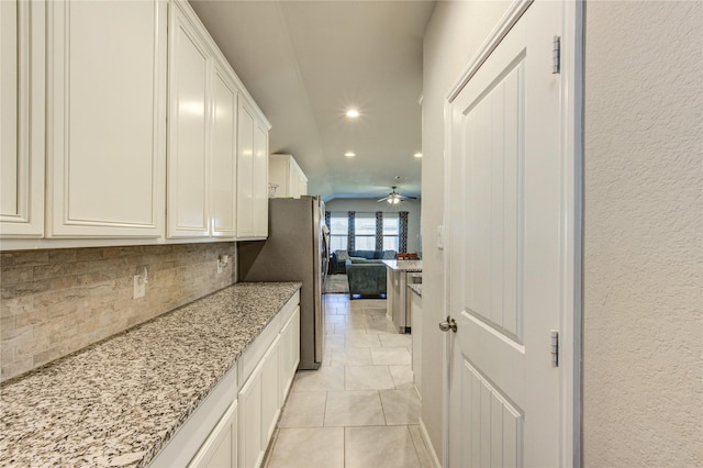 kitchen featuring backsplash, white cabinets, light stone counters, and light tile patterned floors