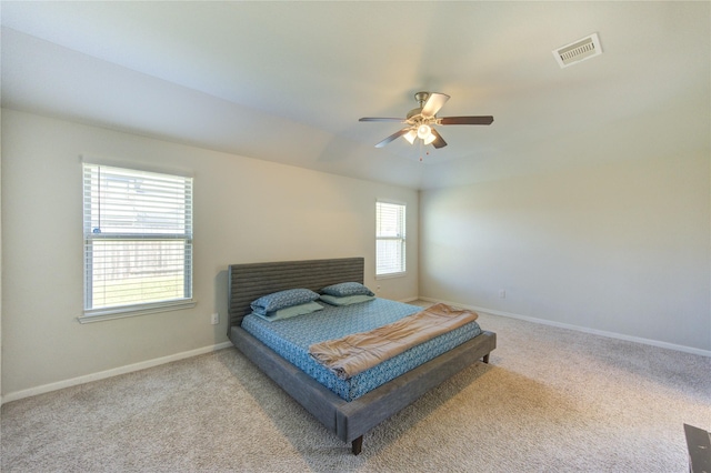 carpeted bedroom with baseboards, a ceiling fan, and visible vents