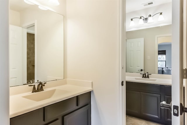 bathroom with visible vents, two vanities, and a sink