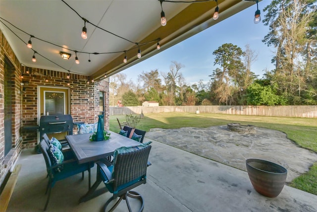 view of patio featuring grilling area, a fenced backyard, outdoor dining space, and an outdoor fire pit