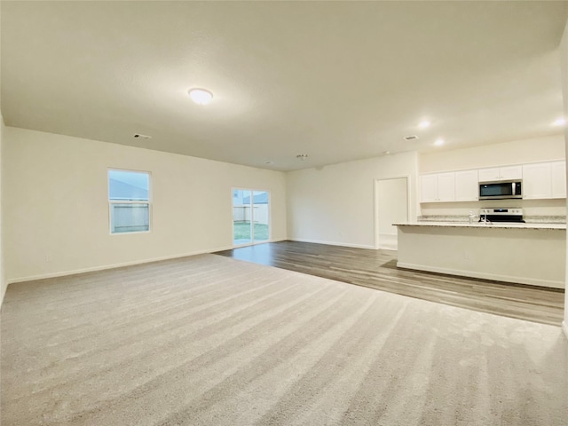 unfurnished living room with visible vents, baseboards, and carpet floors