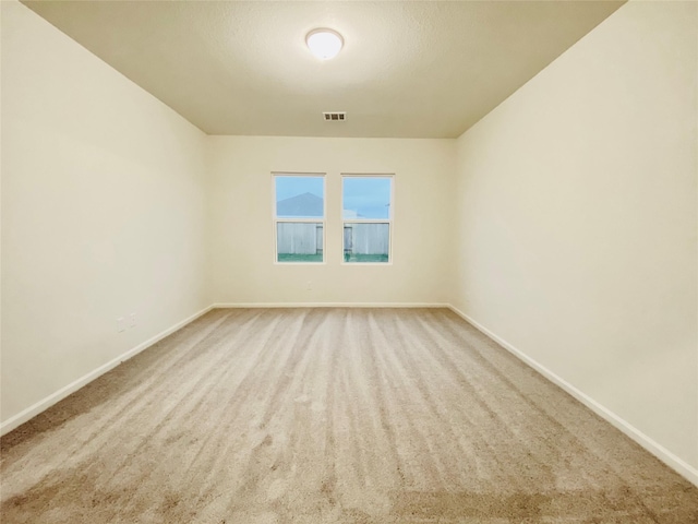 carpeted empty room featuring visible vents and baseboards