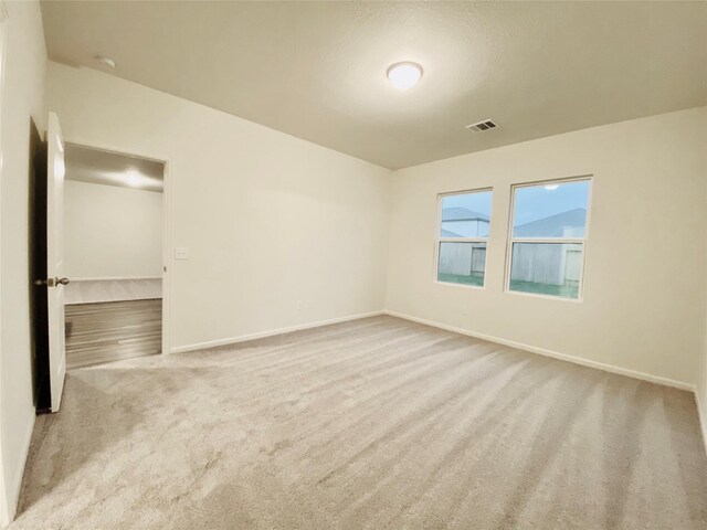 carpeted empty room with baseboards and visible vents