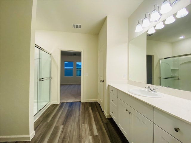 bathroom featuring a shower stall, wood finished floors, vanity, and visible vents