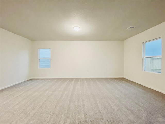 spare room with carpet flooring, visible vents, and baseboards