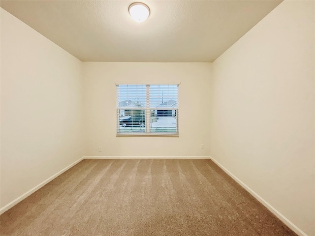carpeted spare room featuring baseboards