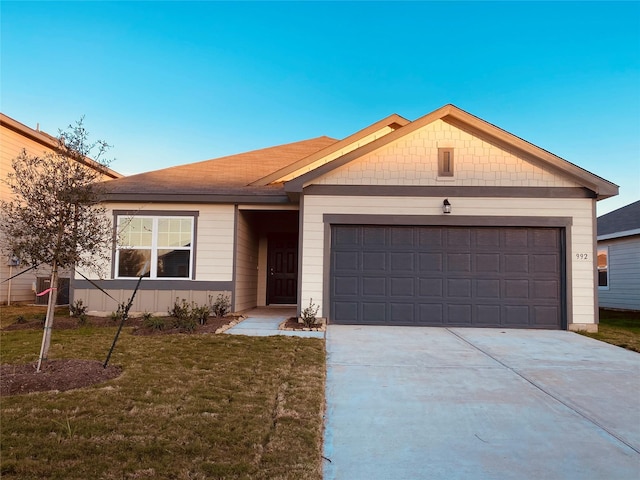 ranch-style home featuring an attached garage, concrete driveway, and a front yard