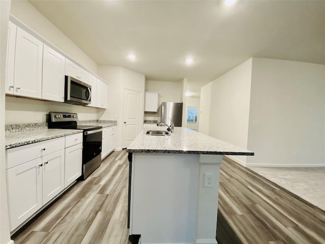 kitchen featuring a center island with sink, a sink, white cabinetry, and stainless steel appliances