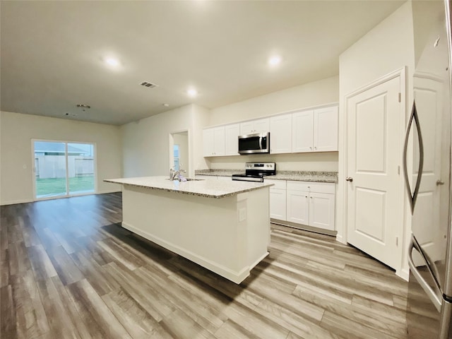 kitchen with visible vents, white cabinets, a sink, light wood-type flooring, and stainless steel appliances