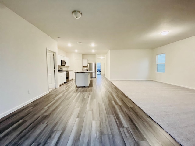 unfurnished living room featuring baseboards and wood finished floors