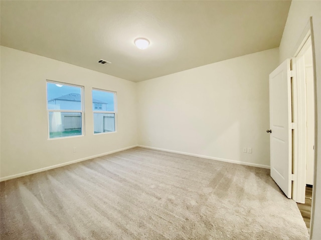 empty room featuring light colored carpet, baseboards, and visible vents