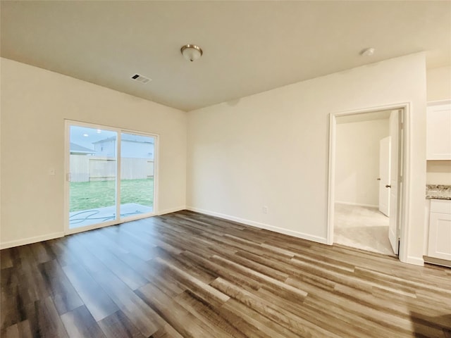 unfurnished room featuring visible vents, baseboards, and wood finished floors