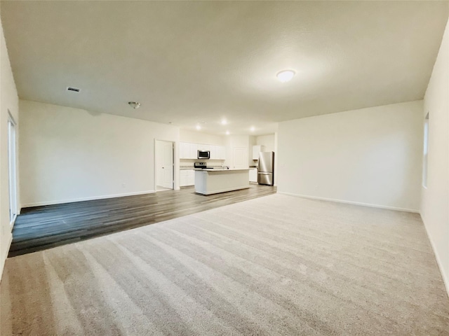 unfurnished living room featuring visible vents, baseboards, and carpet flooring