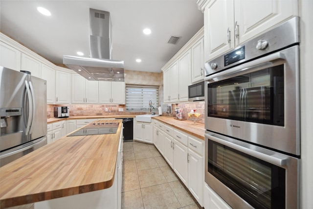12538 W Pavilion Ct W, Tomball, TX 77377 - kitchen with wood counters, black appliances, island range hood, white cabinetry, and recessed lighting