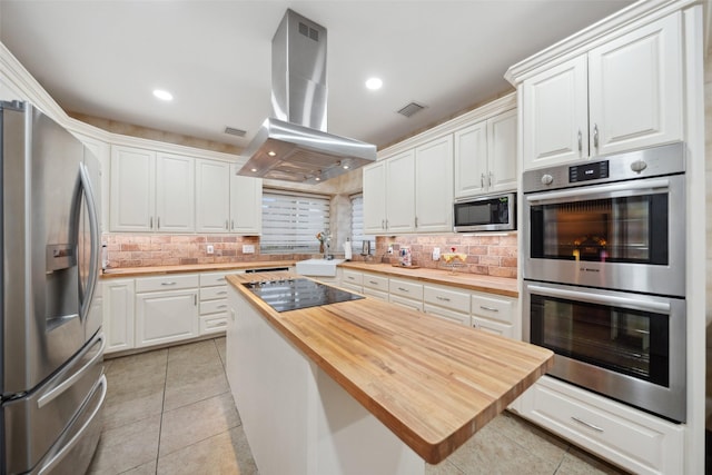 12538 W Pavilion Ct W, Tomball, TX 77377 - kitchen with stainless steel appliances, butcher block counters, island range hood, white cabinetry, and decorative backsplash