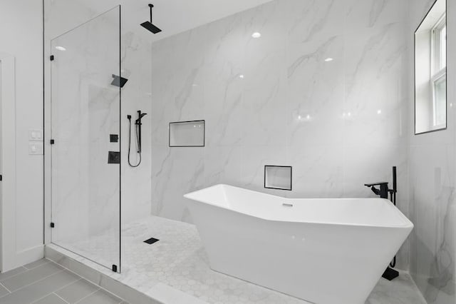 full bath featuring a marble finish shower, tile walls, and a soaking tub