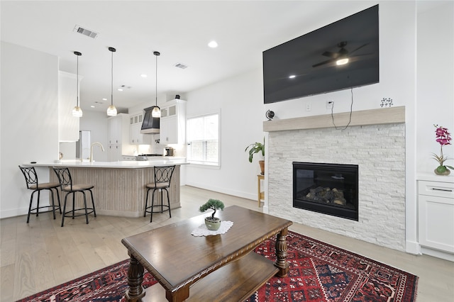 living area featuring visible vents, baseboards, light wood-type flooring, and a fireplace