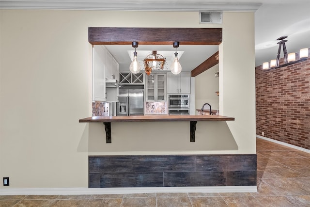 53 Litchfield Ln, Houston, TX 77024 - kitchen with stainless steel appliances, brick wall, glass insert cabinets, wooden counters, and a breakfast bar area