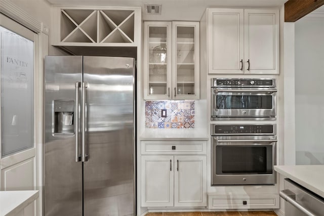 53 Litchfield Ln, Houston, TX 77024 - kitchen featuring stainless steel appliances, light countertops, glass insert cabinets, and white cabinets