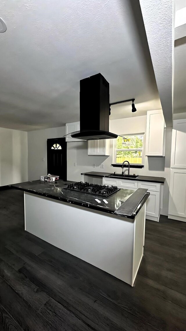 6416 Eagle Pass St, Houston, TX 77020 - kitchen featuring island range hood, dark countertops, a sink, dark wood-style floors, and white cabinetry