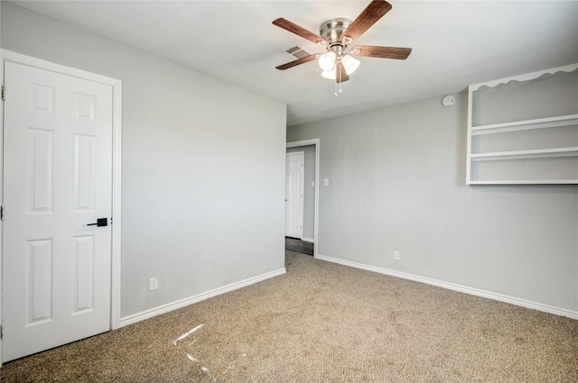 empty room featuring carpet flooring, visible vents, baseboards, and ceiling fan