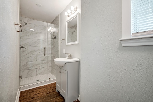 full bath with a textured wall, vanity, and a stall shower