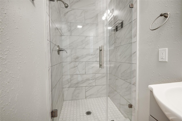 full bathroom with a shower stall, vanity, and a textured wall
