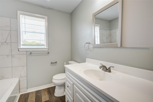 bathroom with toilet, vanity, wood finished floors, and a healthy amount of sunlight