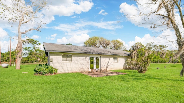 back of property with a yard, a patio, and french doors