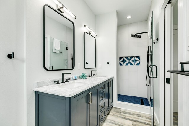 full bathroom with tiled shower, wood finished floors, a sink, and recessed lighting