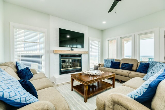 living room with a brick fireplace, a ceiling fan, plenty of natural light, and recessed lighting