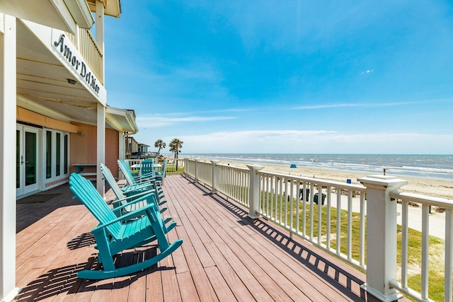 wooden deck with a water view and a view of the beach