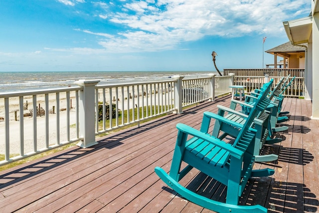 wooden terrace with a view of the beach and a water view