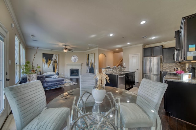 6303 Wood Creek Ln, League City, TX 77573 - dining space with crown molding, light wood-style flooring, a ceiling fan, and a fireplace