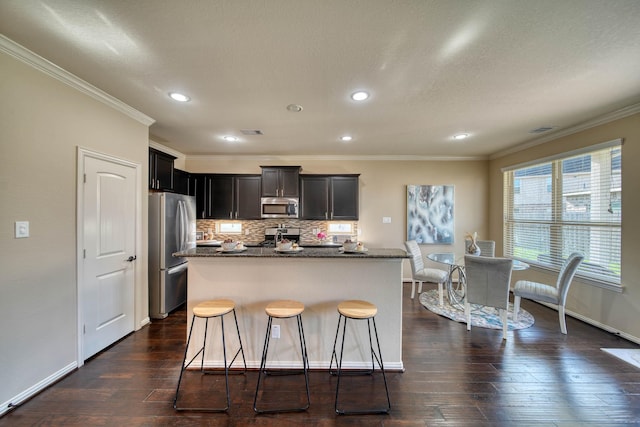 6303 Wood Creek Ln, League City, TX 77573 - kitchen featuring ornamental molding, a center island, backsplash, dark wood finished floors, and appliances with stainless steel finishes
