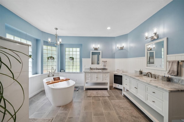 14832 Oak Shores Dr, Willis, TX 77318 - bathroom with a wainscoted wall, a chandelier, a freestanding bath, and two vanities
