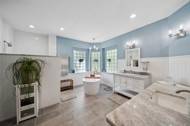 14832 Oak Shores Dr, Willis, TX 77318 - full bath with a wainscoted wall, a chandelier, two vanities, a freestanding bath, and recessed lighting