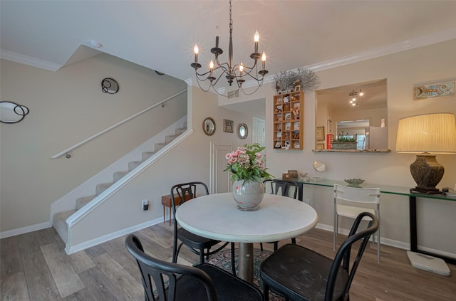 dining space with baseboards, a chandelier, crown molding, wood finished floors, and stairs