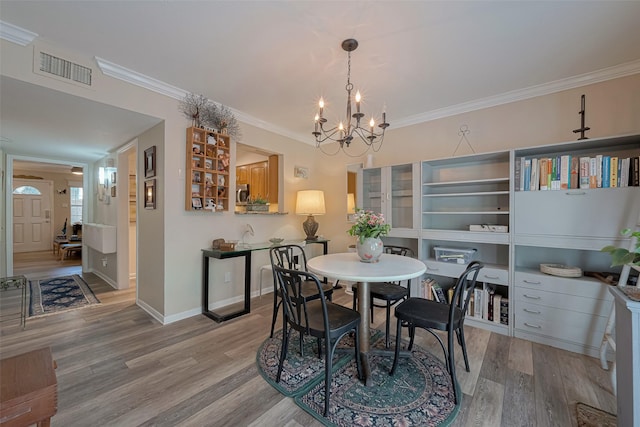 dining room with visible vents, ornamental molding, an inviting chandelier, and wood finished floors