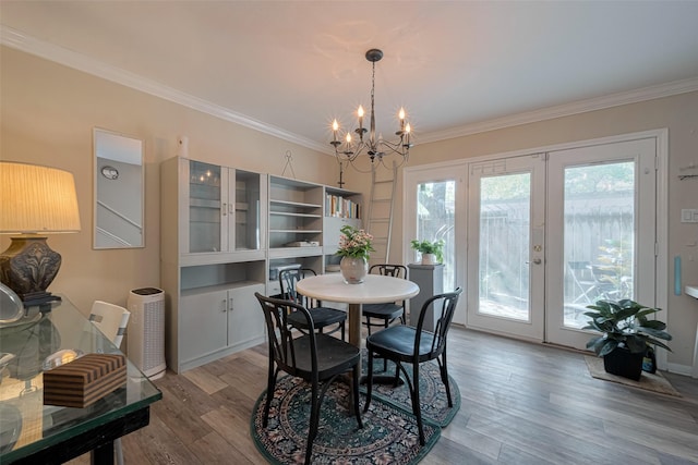 dining area with crown molding, french doors, an inviting chandelier, and wood finished floors